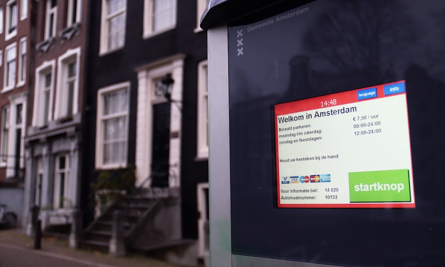 Display of a Gemeente Amsterdam parking machine in front of canal houses.