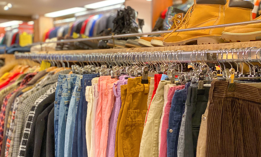 Different coloured trousers and shirts on the rack