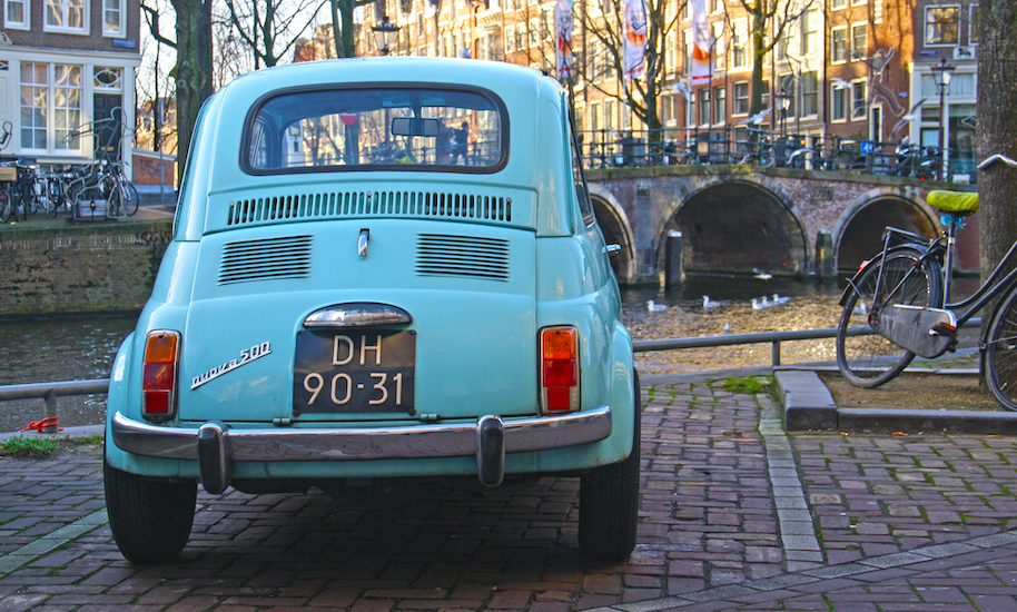 A parked light blue Fiat 500 in the Amsterdam canal belt