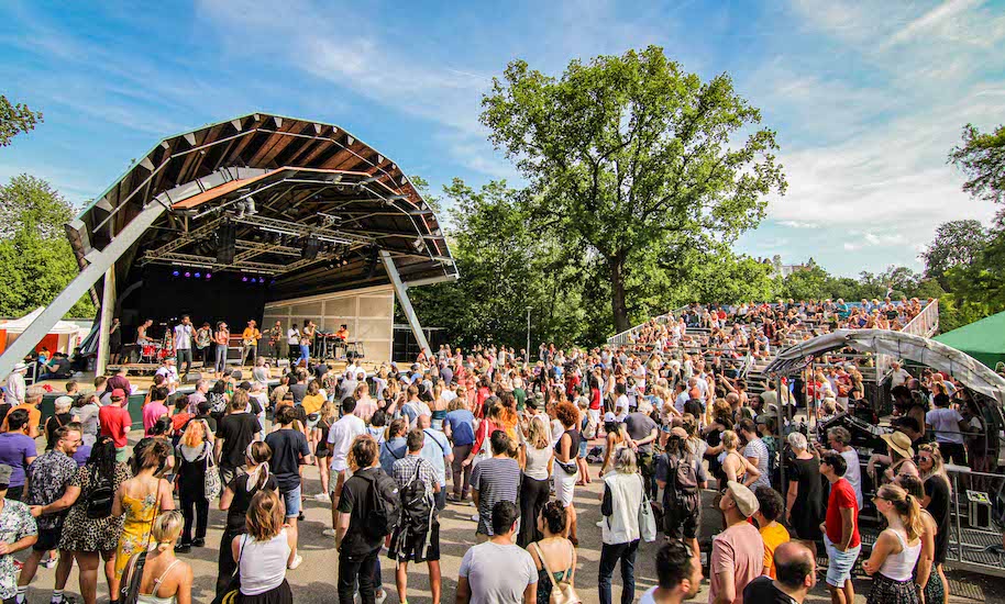 Many people stand in front of the stage at the Vondelpark Amsterdam Openlucht Theatre